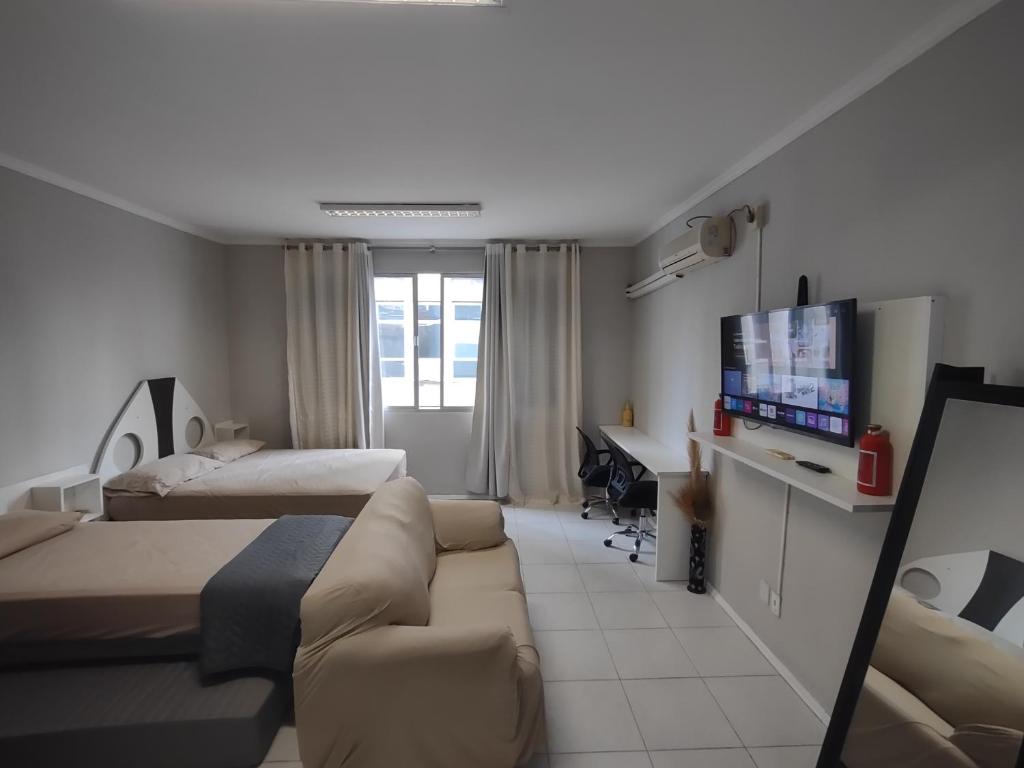 a room with two beds and a couch and a television at Apto Studio 202 centro floripa in Florianópolis