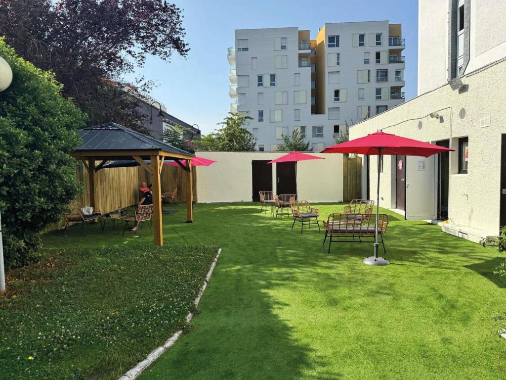 un patio con mesas y sombrillas en Ibis Styles Paris Saint Denis La Plaine, en Saint-Denis