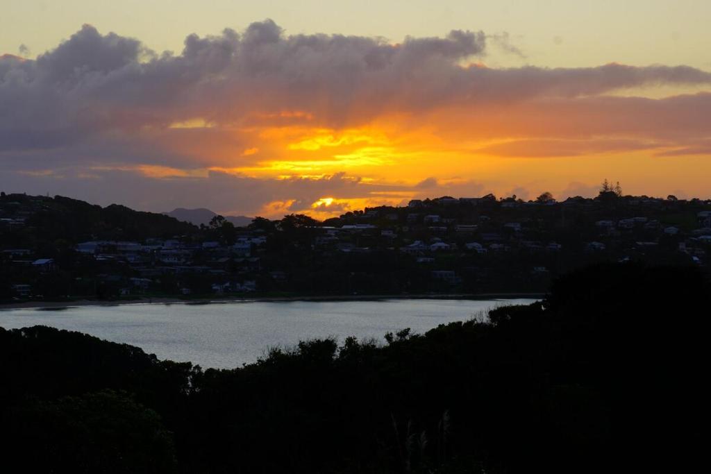 un coucher de soleil sur une étendue d'eau avec une ville dans l'établissement House close to Oneroa Village, beach, and wineries, à Waiheke Island