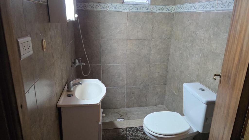 a bathroom with a white toilet and a sink at Hospedaje La Cabaña in San Miguel del Monte