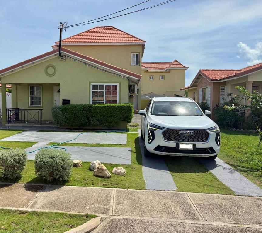 a white car parked in front of a house at Cozy Retreat in Gated Portmore Country Club in Portmore
