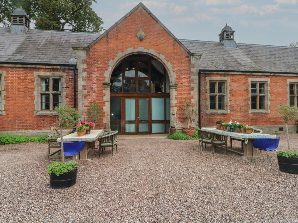 a brick building with tables and chairs in front of it at Diamond Lodge in Ingestre