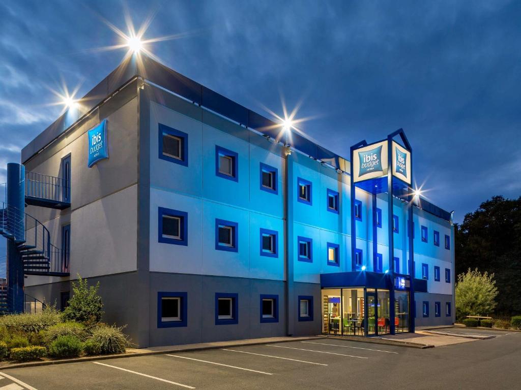 a blue building with lights on top of it at Ibis Budget Angers Parc des Expositions in Saint-Sylvain-dʼAnjou