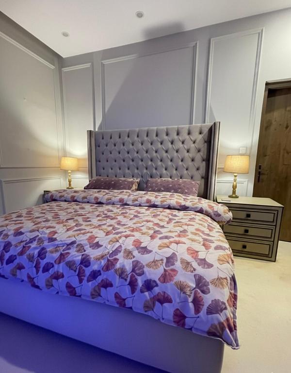 a bedroom with a bed with a purple comforter and two lamps at Luxury Lodge in Rawalpindi