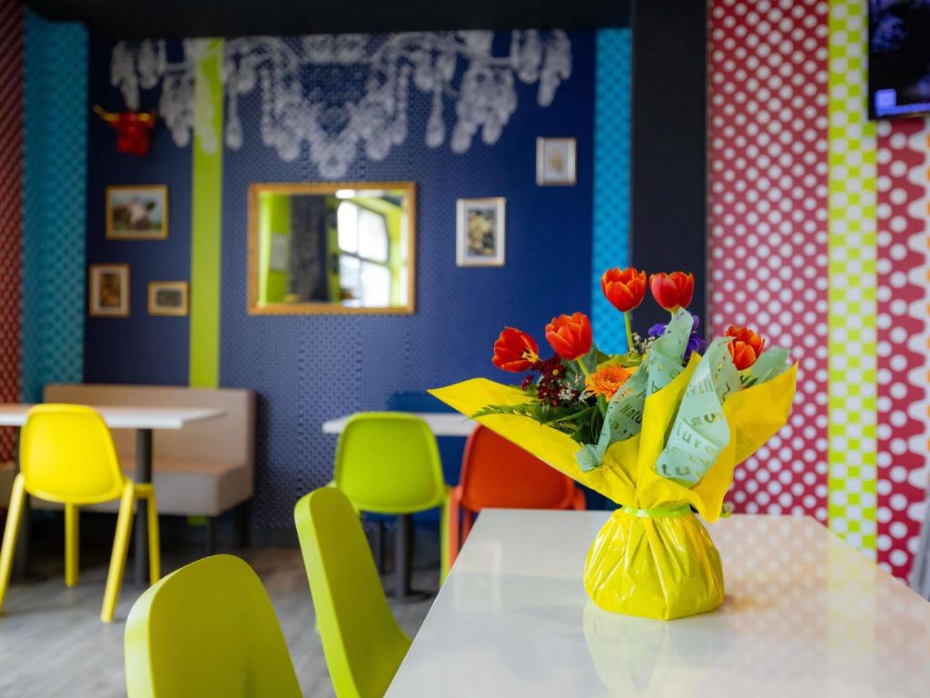 a table with a vase of red flowers on it at ibis budget Besançon Centre Gare in Besançon