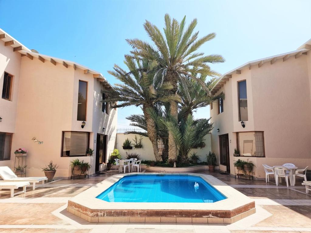 una piscina di fronte a un edificio con una palma di Condominio 4 Estaciones a Paracas