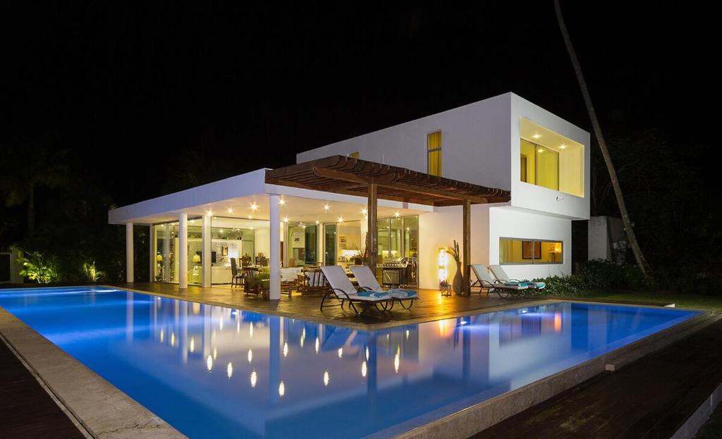 a swimming pool in front of a house at night at Luxurious beachfront house Las Brisa in El Limón
