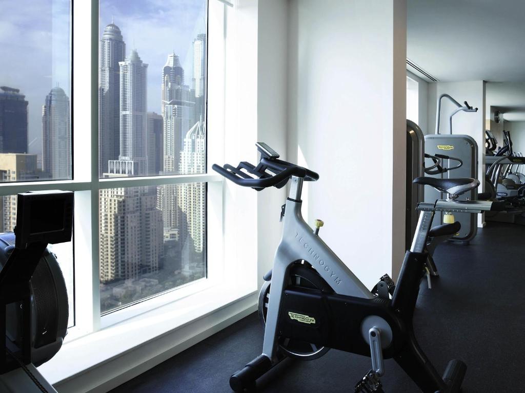 a gym with a view of a city from a window at Pullman Dubai Jumeirah Lakes Towers in Dubai