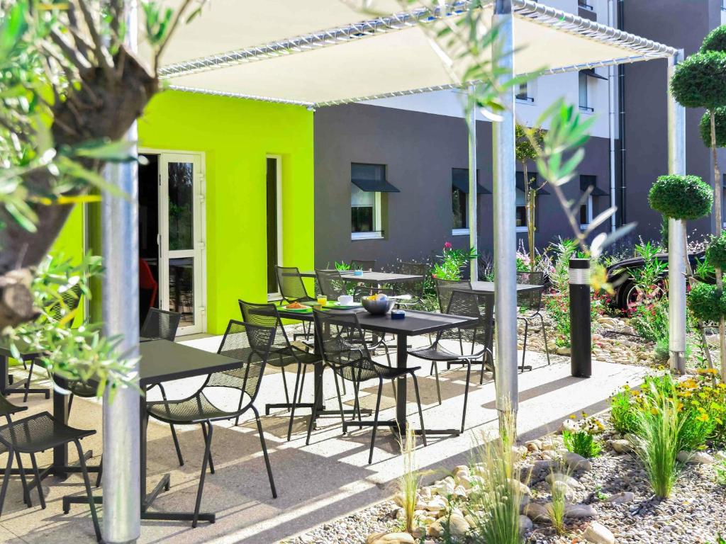 a patio with tables and chairs in a garden at Ibis Budget Porte de Camargue in Saint-Martin-de-Crau