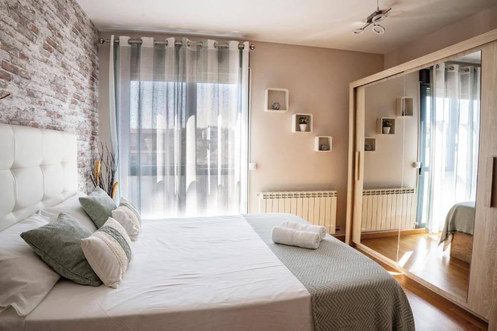 a bedroom with a white bed with a brick wall at Rincón del Naranjo in Olite