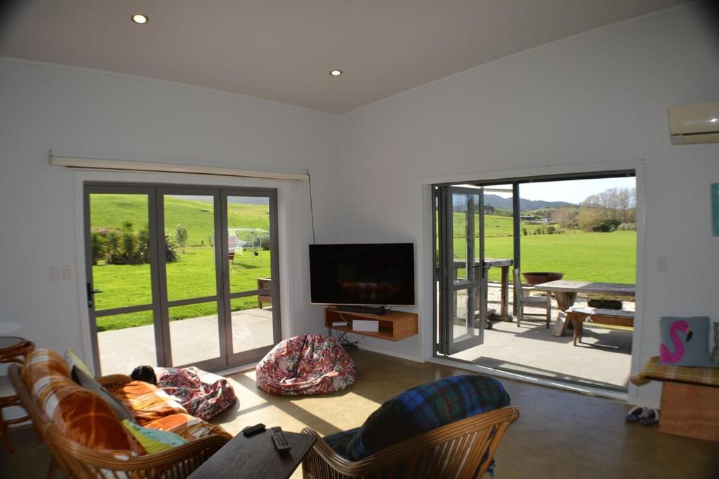 un soggiorno con divano, TV e patio di Magical property close to Mangawhai a Mangawhai