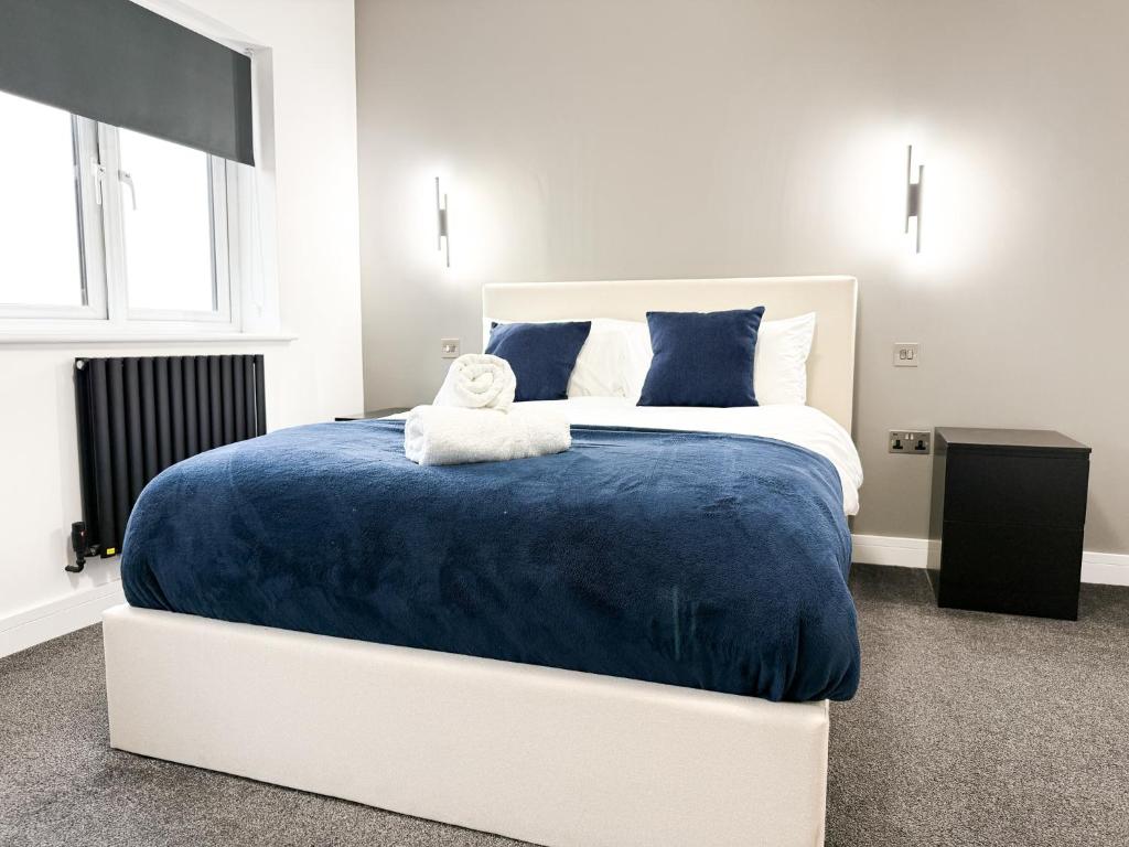 Un dormitorio con una cama grande con una manta azul. en The Aurora Apartments, en Peterborough