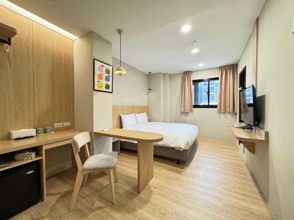 a hotel room with a bed and a desk and a desk at Yoshi Hotel - Tainan Sinmei Branch in Tainan