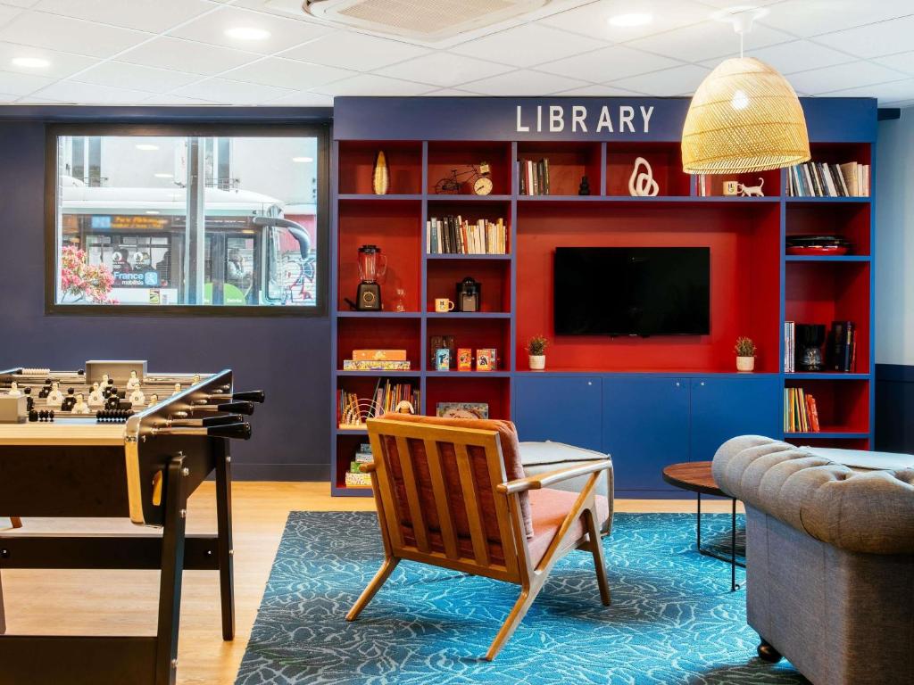 a living room with a library with a tv and a chair at Aparthotel Adagio Paris Malakoff Chatillon in Malakoff