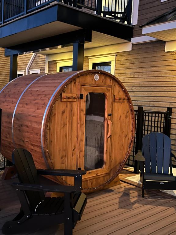 a wooden barrel sitting on a deck with two chairs at Escapade bien-être, en Estrie in Shefford