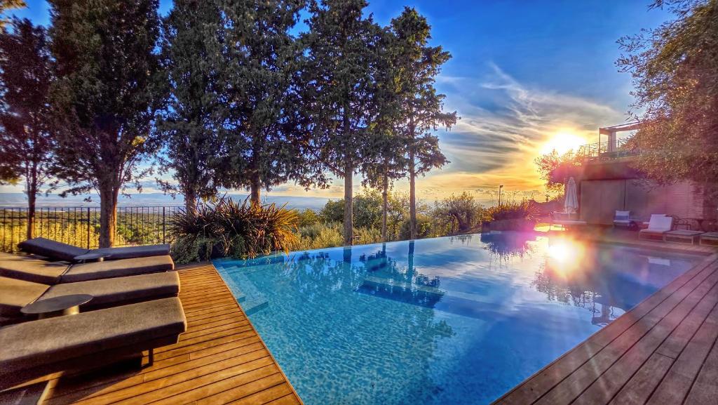 a swimming pool on a wooden deck with a sunset at Rahal Luxury Between Etna & Sea - Heated Jacuzzi & Infinity Pool in Catania
