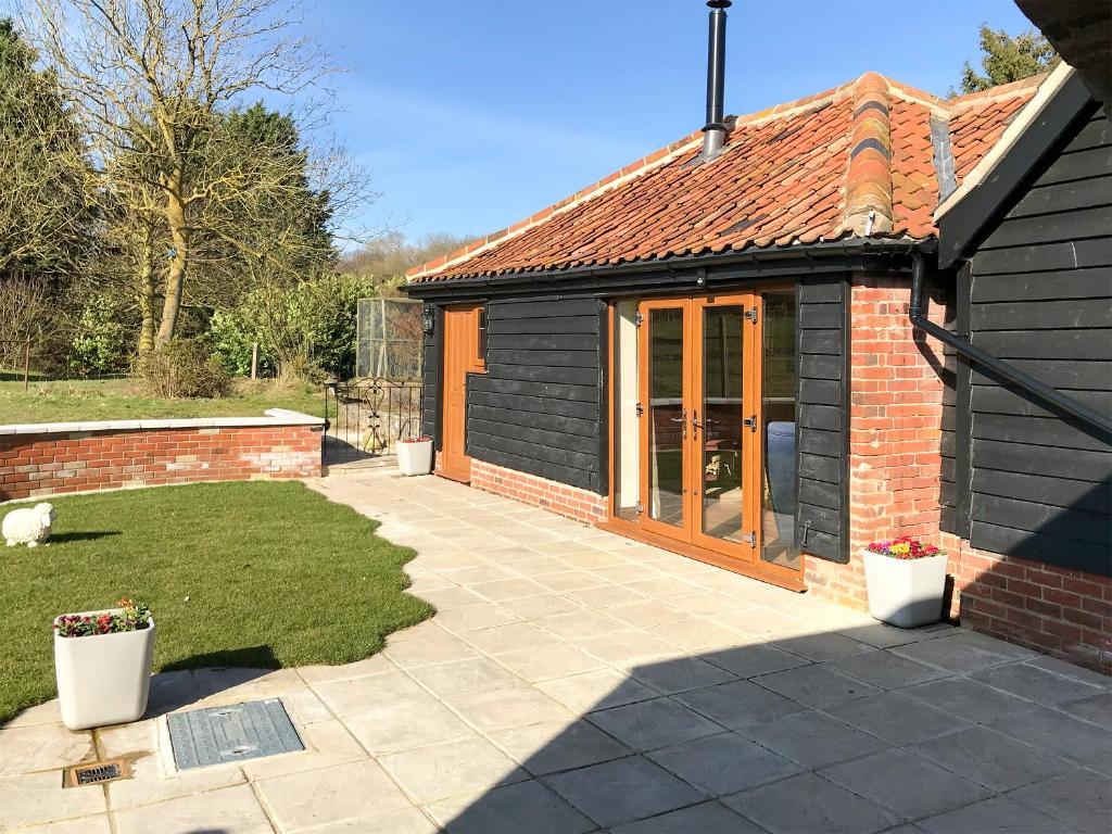 a small house with a patio in a yard at Chick Hatch Barn in Kelsale