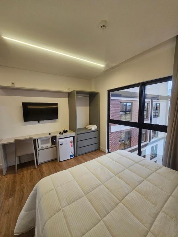 a bedroom with a large bed and a flat screen tv at Suite privada en Four Seasons Residence monoambiente in Bombinhas