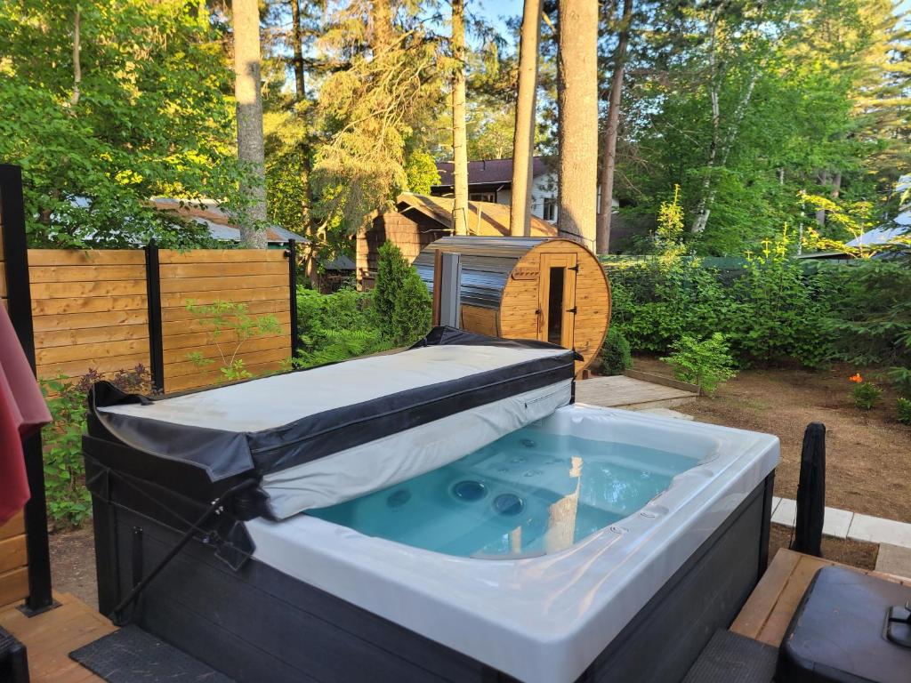 a jacuzzi tub in a backyard with a dog house at Serene Getaway Nordic Spa , Sauna, Nature & Pool in Rawdon