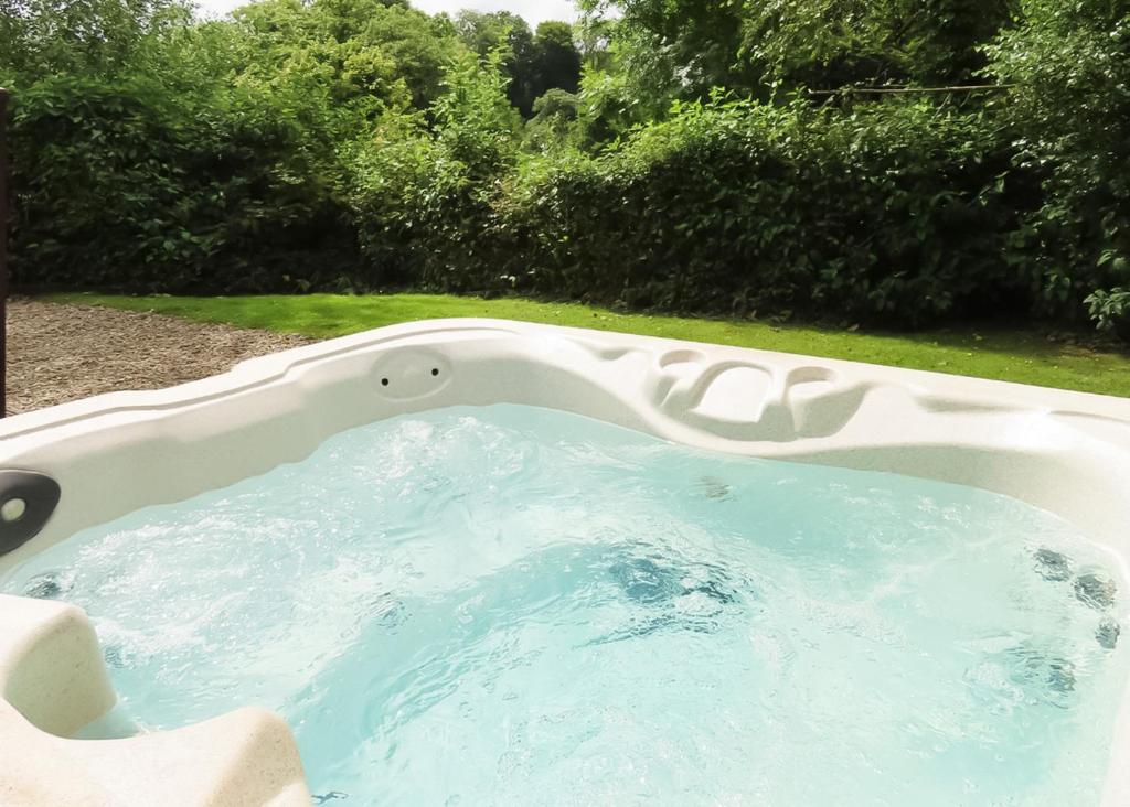 un jacuzzi dans une cour arborée dans l'établissement Herons Brook Retreat Lodges, à Narberth
