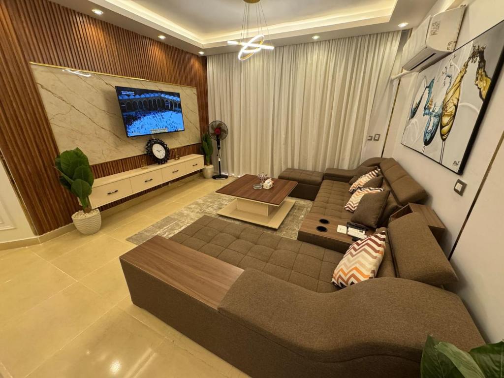 a living room with a couch and a tv at Luxury diamond apartment in wesal residences compound in New cairo