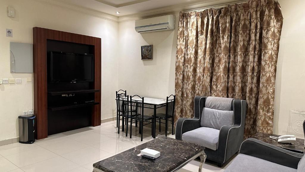 sala de estar con TV, sillas y mesa en سلس للشقق المخدومة - فرع الرفيعة, en Riad
