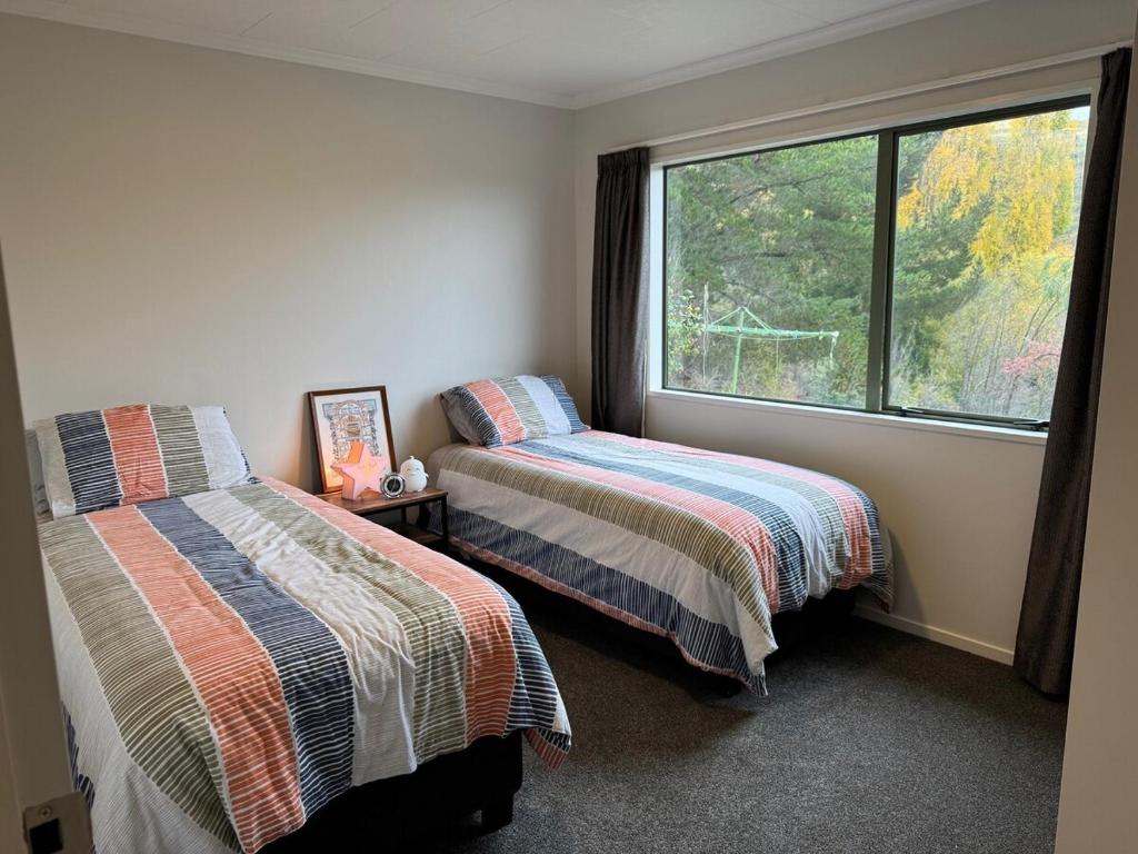 two beds in a room with a window at Entire home in Roxburgh in Roxburgh