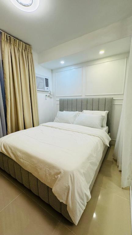 a bedroom with a large white bed with curtains at J Tower Residences in Bakilid