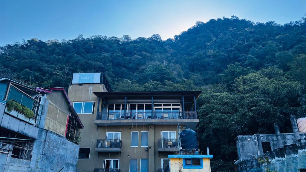 un edificio frente a una montaña con árboles en Hotel Devraj, en Rishīkesh