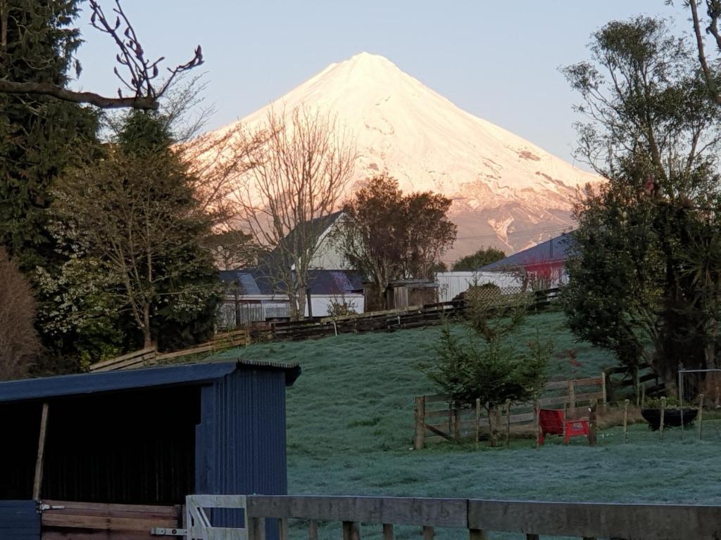 a snow covered mountain in the distance with a building and trees at Cold Ebb Mountain View Homestay 