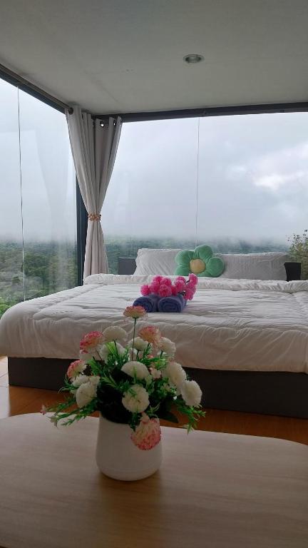 a bedroom with a large bed and a vase with flowers at ไร่ปราณปรียา in Campson