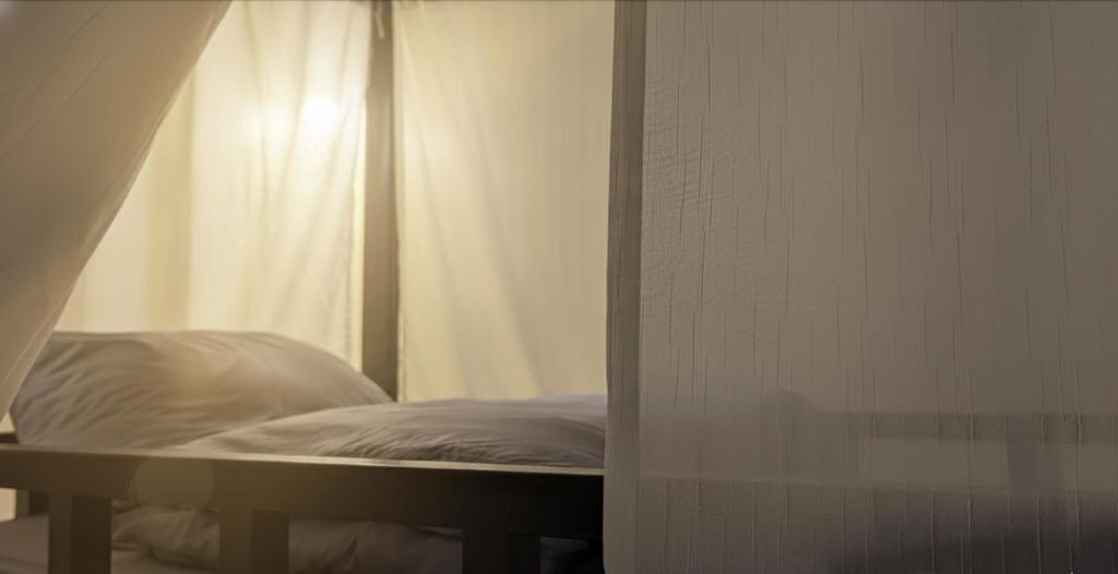 a bed in a room with a white curtain at Non Pakse One Cup Hostel in Pakse