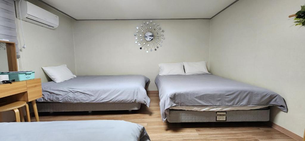 a room with two beds and a clock on the wall at S2 Private Kintex Daehwadong in Goyang