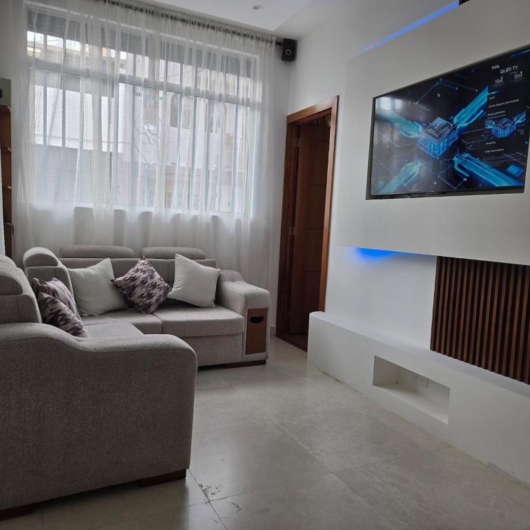 a living room with a couch and a flat screen tv at majesty beautiful suite in Cuenca