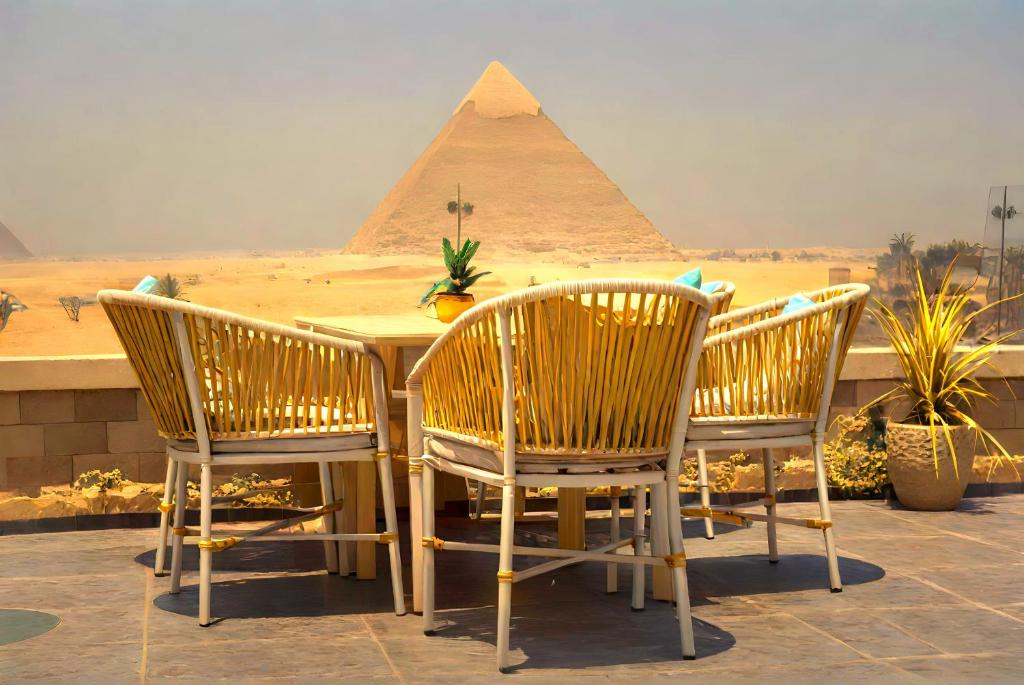 a table and chairs with the pyramids in the background at Pyramids MagiC View Hotel in Cairo