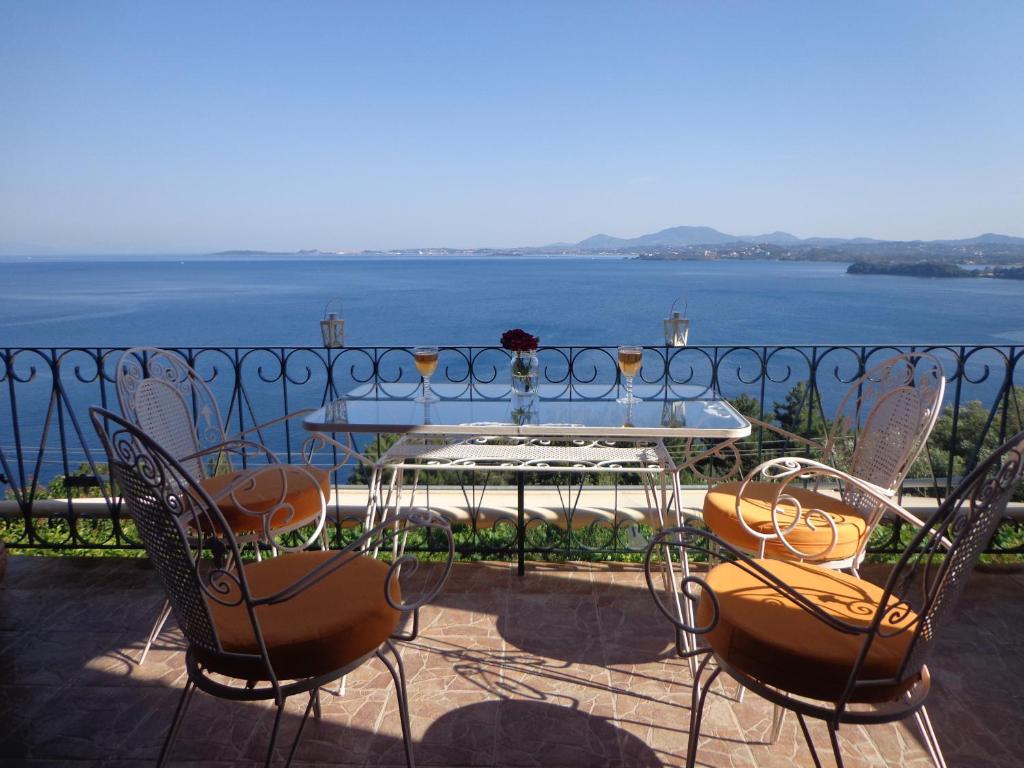 a table and chairs on a balcony with a view of the water at Villa Pergola in Pyrgi