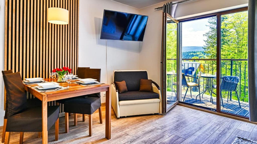 a dining room with a table and chairs and a balcony at Apartament Góry i Las in Szklarska Poręba