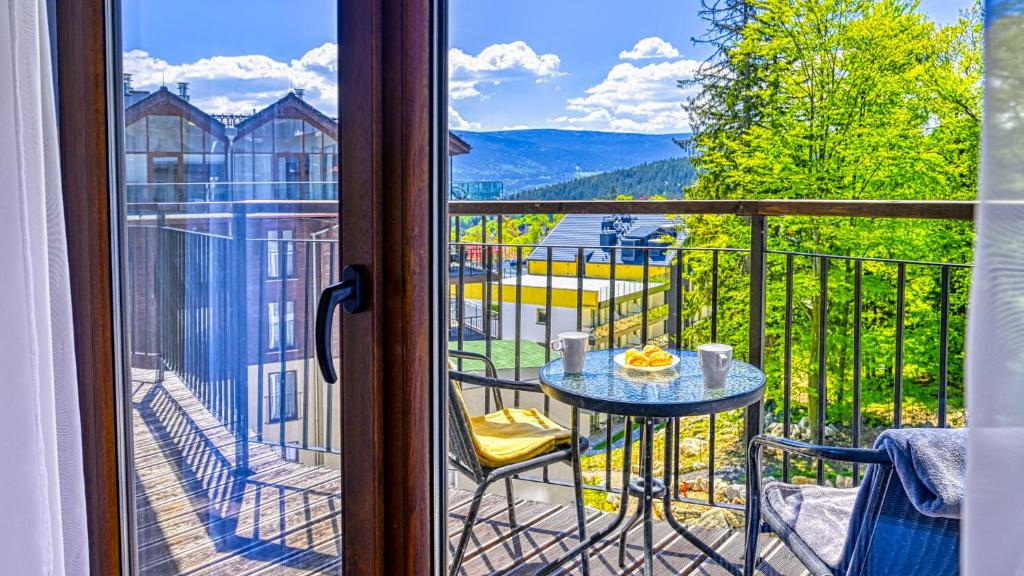 a room with a balcony with a table and a view at Apartament Góry Las in Szklarska Poręba
