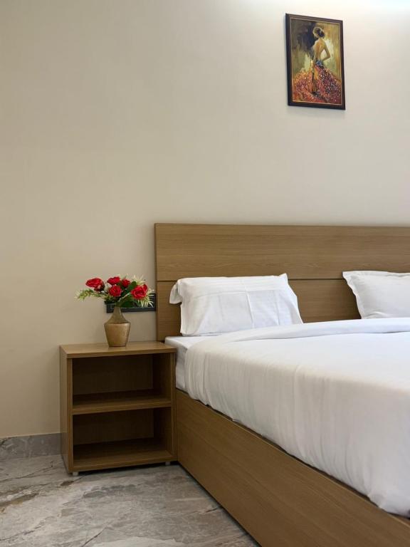 a bedroom with a large bed and a vase of flowers at Hotel Abline Rishikesh in Rishīkesh