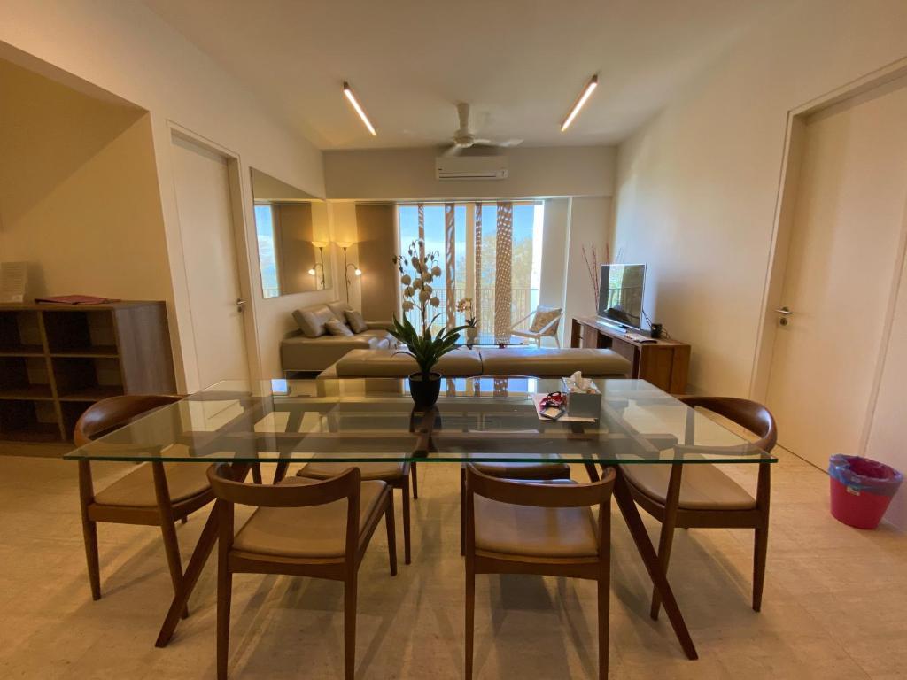 a living room with a glass table and chairs at By The Sea@ Cozy Beachfront Home (Batu Ferringhi). in Batu Ferringhi