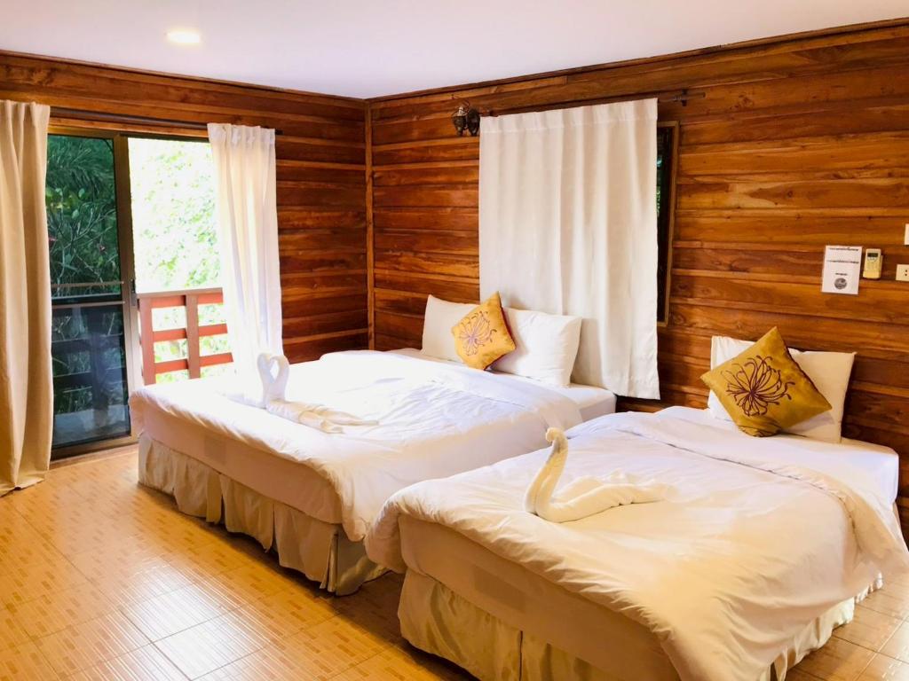 two beds in a room with wooden walls at ศศิคันทรี รีสอร์ท in Suan Phung