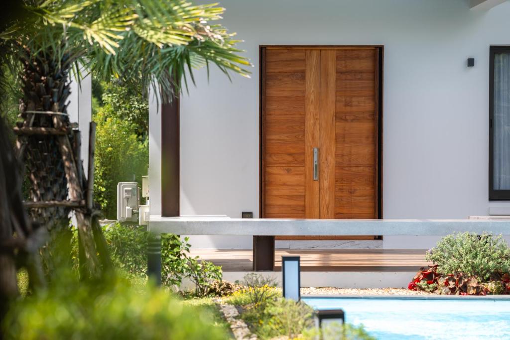 a house with a wooden door and a bench at Lanna Fusion in Hang Dong