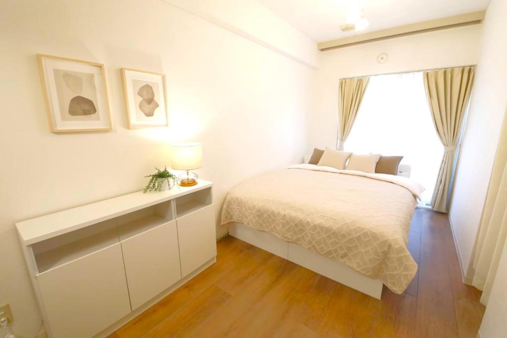 a white bedroom with a bed and a window at Vermidor Ebisu302 in Tokyo