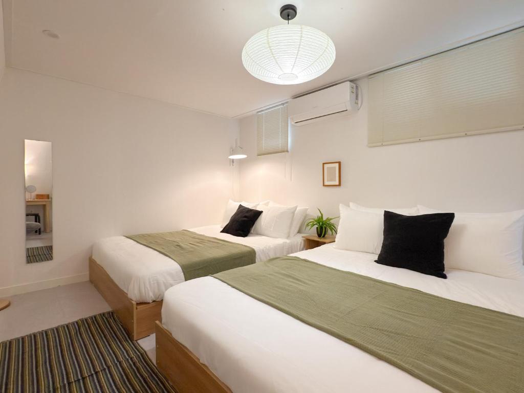 Dos camas en una habitación con paredes blancas. en 스테이프랑, en Seúl