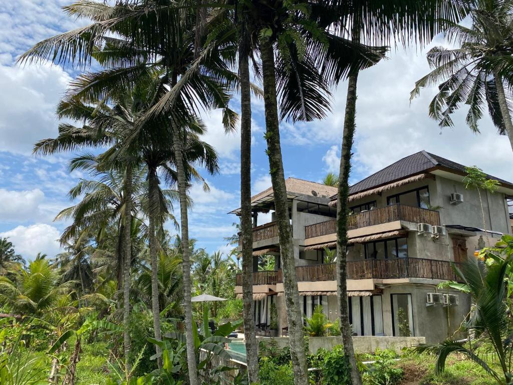 a building with palm trees in front of it at Bali View Ubud Hotel in Ubud