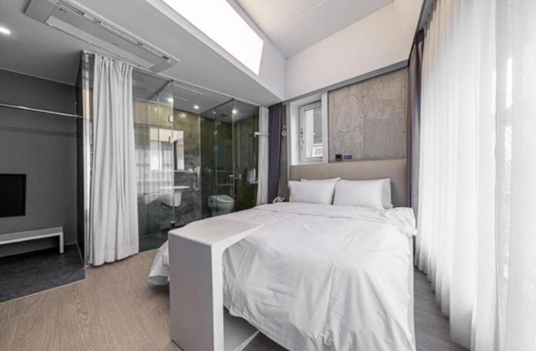 a bedroom with a large white bed and a bathroom at 구로 서울 인 호텔 in Seoul