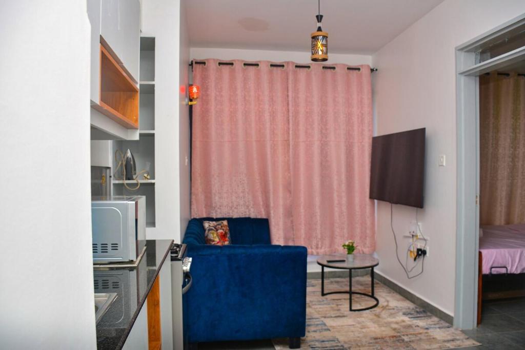 a living room with a blue chair and a television at Tsavo Stanley kiambu Road in Gatunga