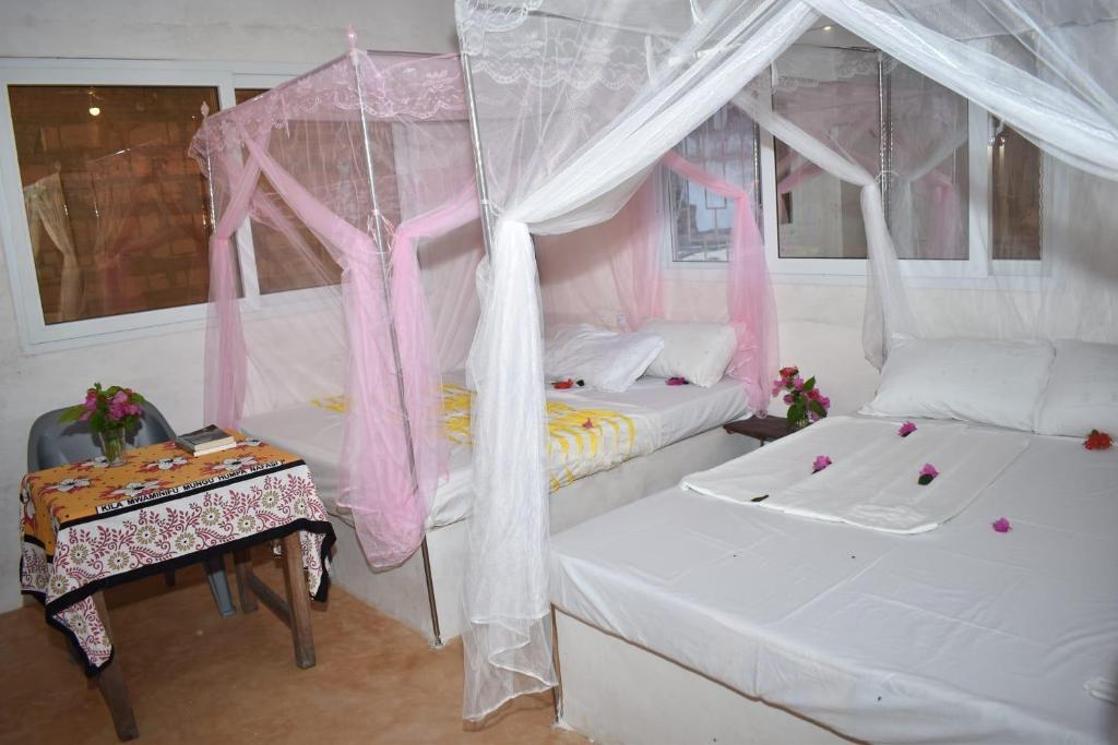 a bedroom with two beds with pink drapes and a table at Amani Guest House Lamu in Lamu