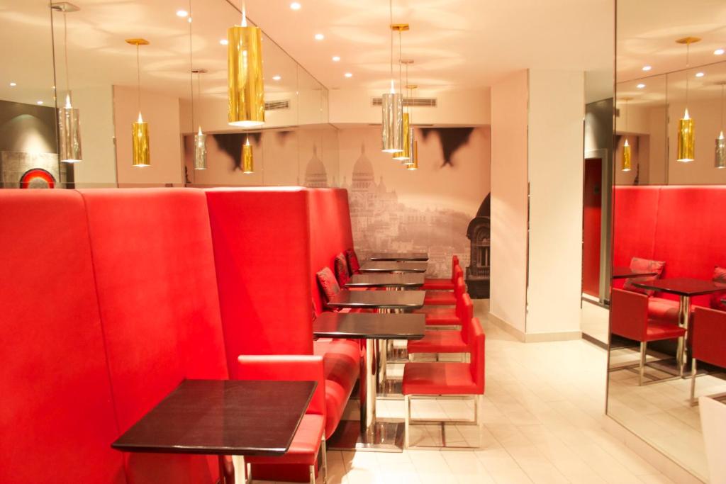 a row of tables and red chairs in a restaurant at Villathena in Paris