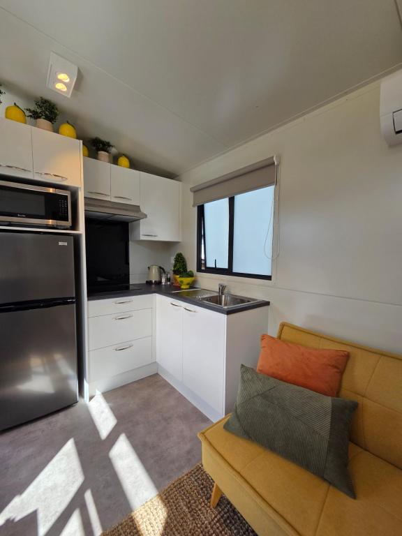 een keuken met een bank en een wastafel in de kamer bij Puriri Tiny Home in Orewa